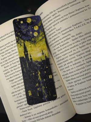 Zakładka 3D z motywem nocnego miasta, leżąca na otwartej książce