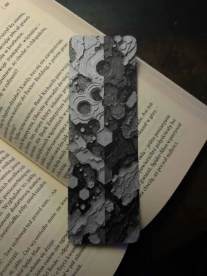 Zakładka 3D „Equinox” z technicznym wzorem w odcieniach szarości, umieszczona na otwartej książce