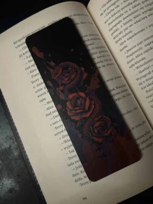 Zakładka 3D z wężem i różami leżąca na otwartej książce