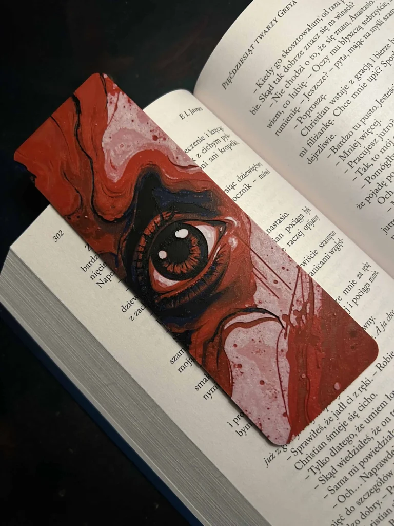 Zakładka 3D „Promieniowanie” z motywem oka, leżąca w książce